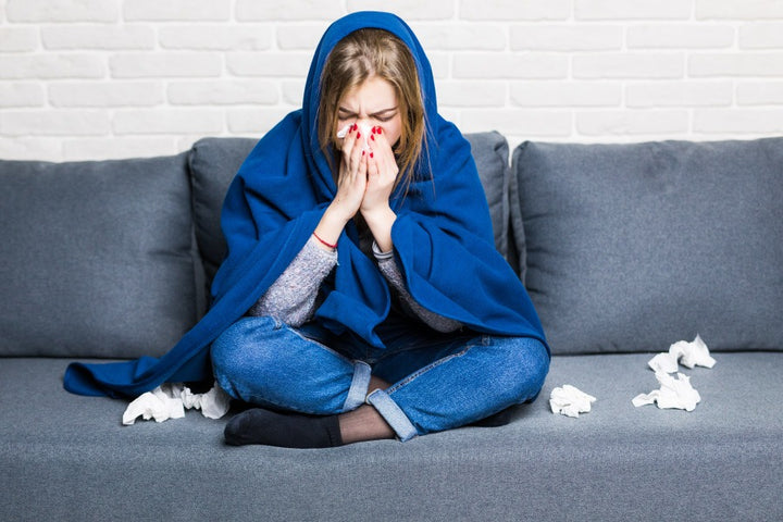 a woman suffering from cold & flu is sitting on her sofa | 8 Foods to Eat & Avoid When You Have Flu