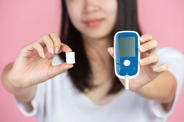 a woman holding a sugar cube on one hand and a glucometer on other hand | skin specialist