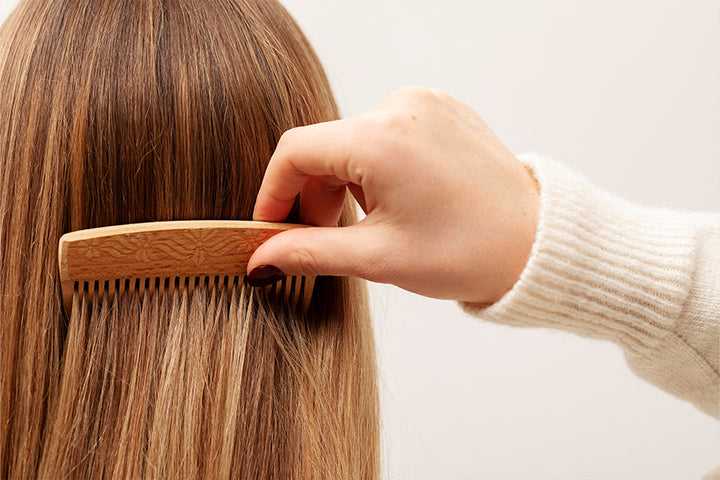Closeup of hair brushing hand | wooden comb benefits