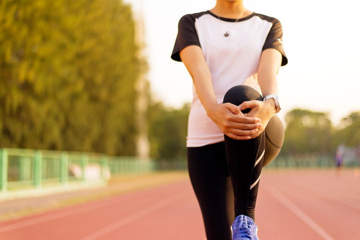 a woman jogging on the track is holding her knee | Best Foods for Tendon Strength