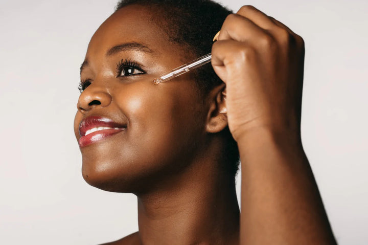 a woman with dark complexion applying serum | how to reduce melanin from skin