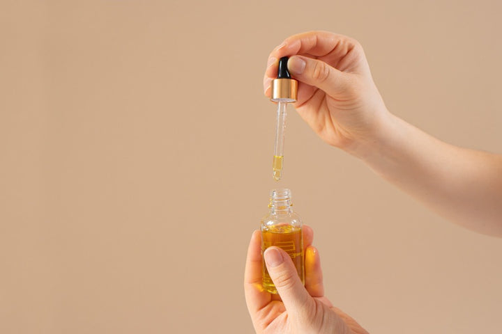 a woman holding a serum and a dropper to be used for getting thicker eyelashes