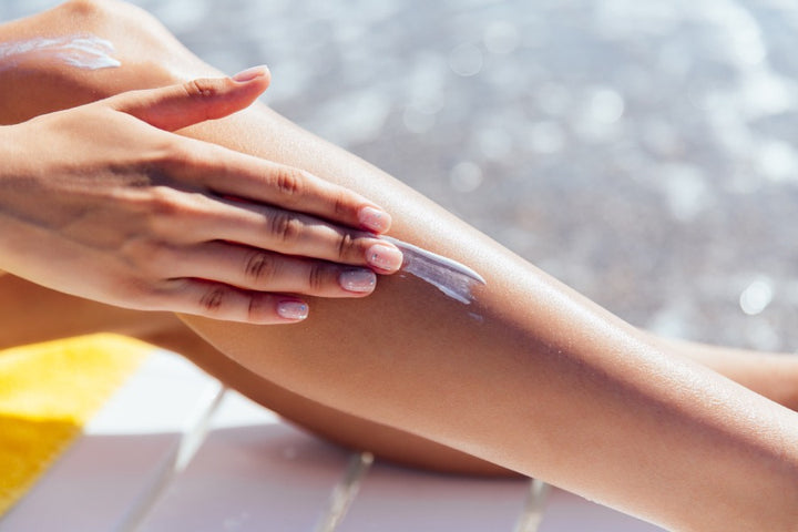 a woman applying sunscreen on her skin to improve skin immunity