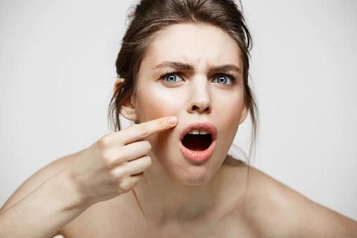 a girl looking at a pimple on her face