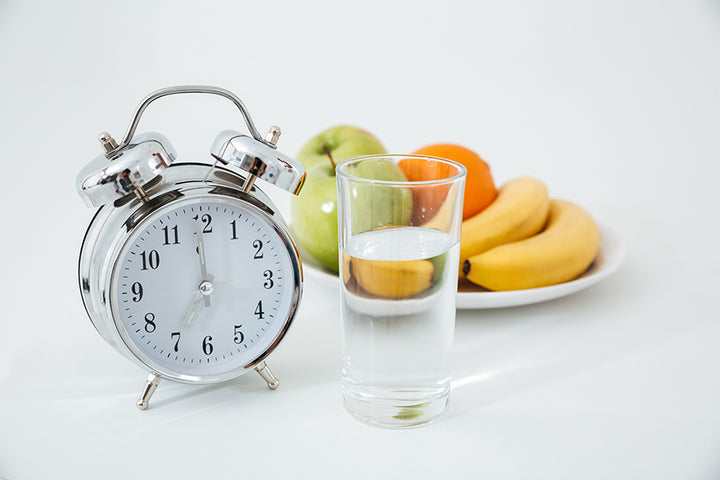 A clock, a glass of water and fruits kept in a plate | how to do intermittent fasting