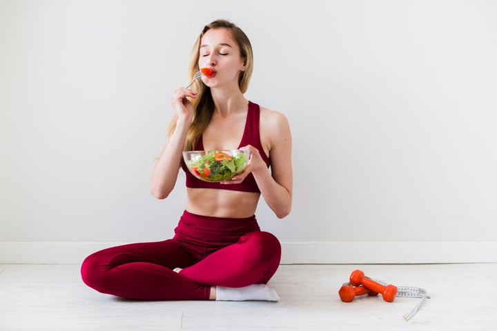 a woman eating fresh fruits and vegetables from a bowl