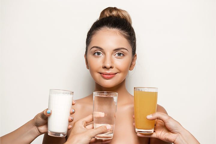 Three hands holding glasses of drinks infront of women | drinks for acne free skin