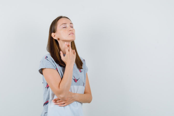 a woman touching her neck | Skin Darkening Due to Thyroid Treatment