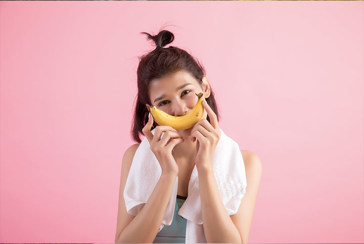 Woman holding banan infront of her face | banana face pack