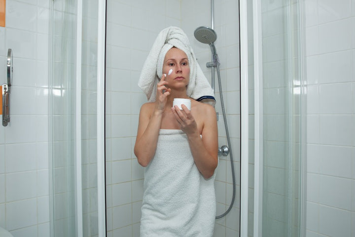 a woman applying cream on her face