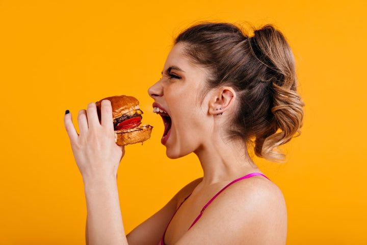 a woman eating a burger | What is an Eating Disorder