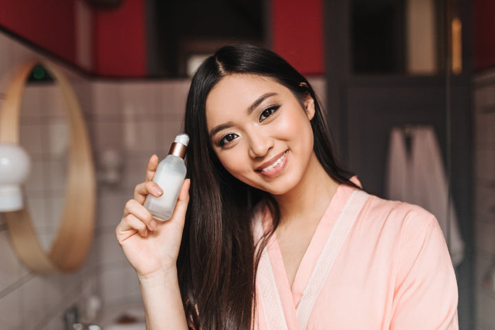 a woman holding an emulsion skincare product