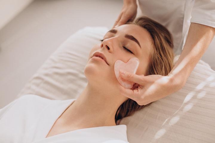 a woman using gua sha facial tool on her face