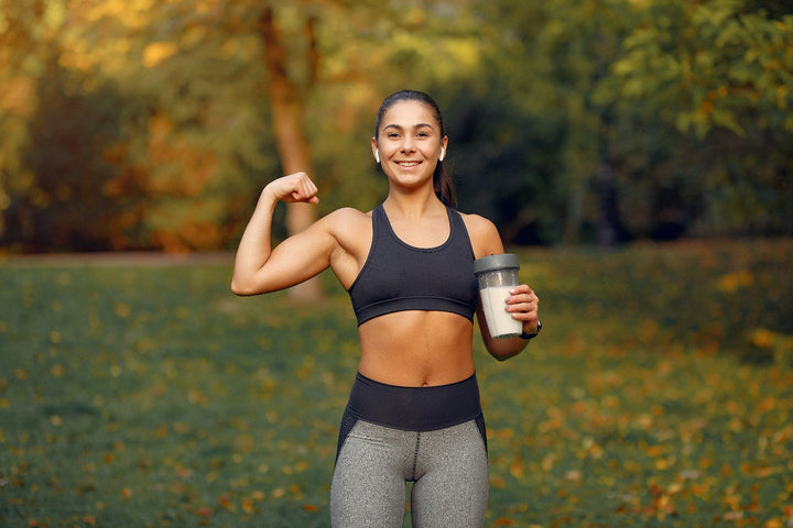 a fit woman holding a bottle of protein shake in one hand