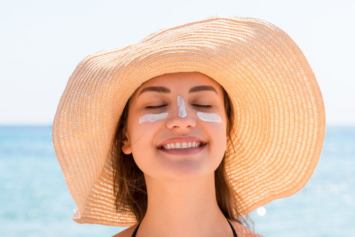 a woman has applied sunscreen on her face and is smiling