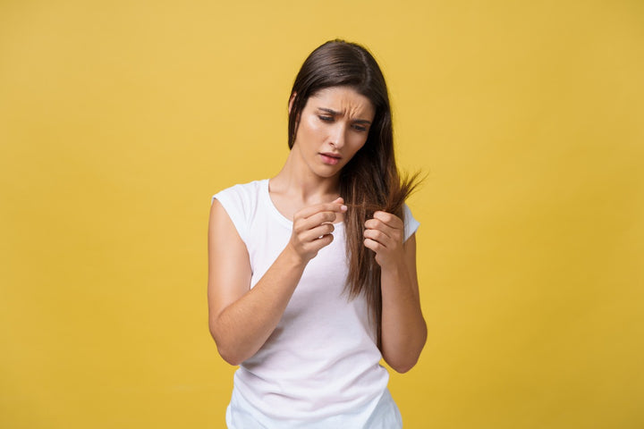 woman hand holding her long hair and staring at her damaged hair