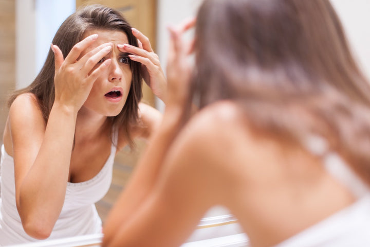 a woman examining her blackheads in the mirror