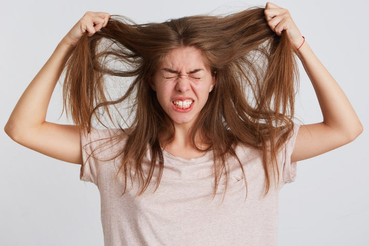 a young woman pulling out her hair in frustration