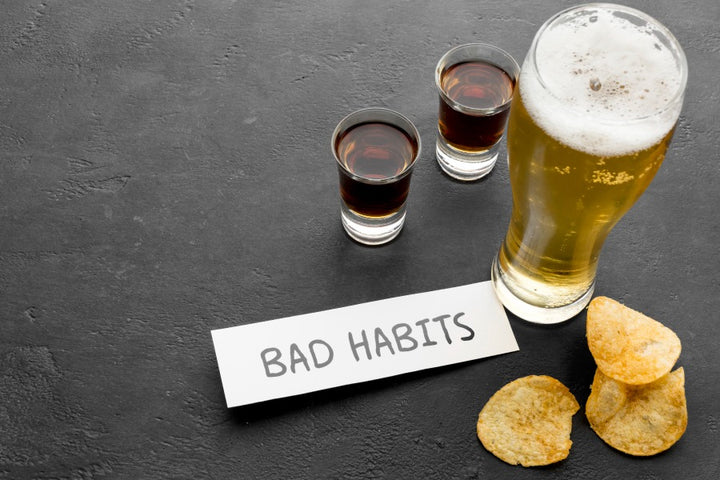 a glass of beer is kept on a table along with bad habits written on a paper note