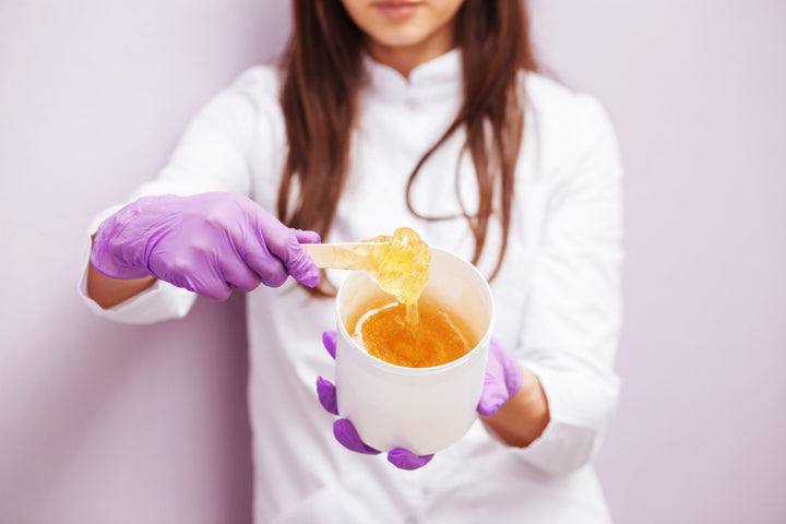 a woman holding a bowl of wax