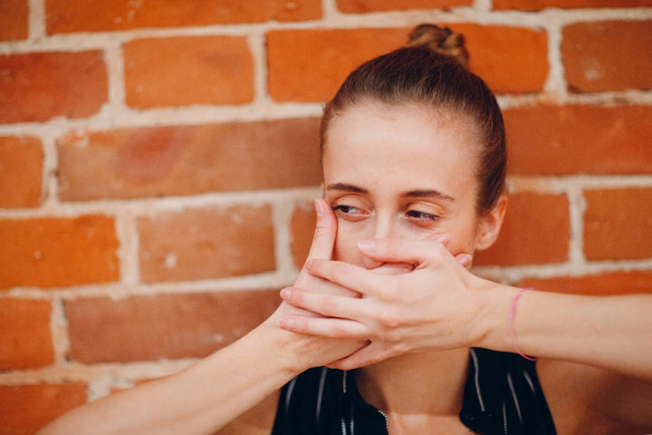 a woman hiding her mouth with her hands