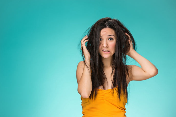 a woman is annoyed with her greasy, oily hair
