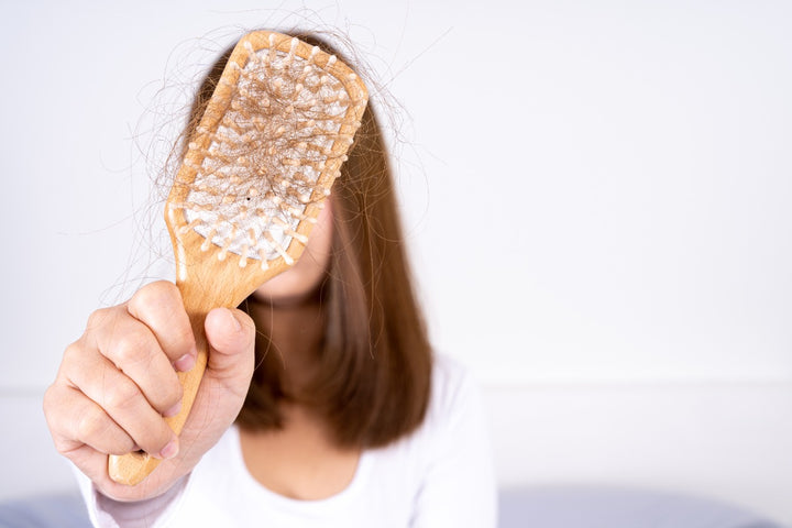 a woman showing a hair brush filled with broken hair