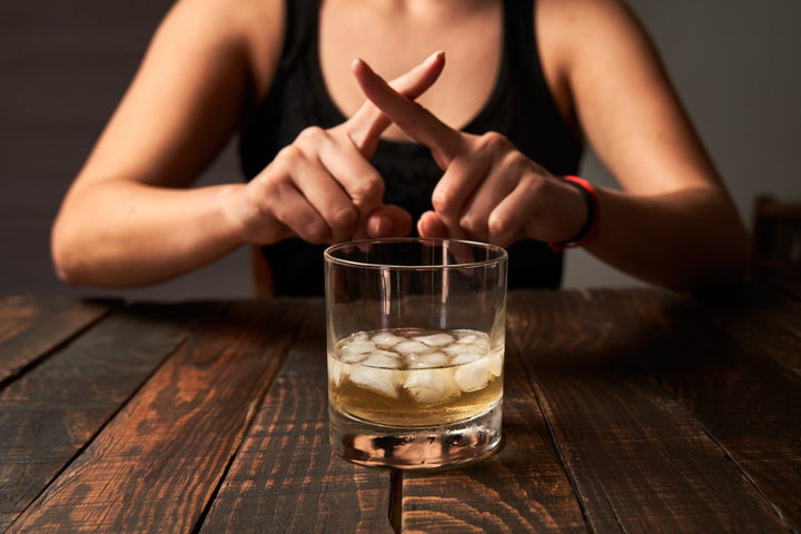 a woman showing crossed fingers to alcohol drinks