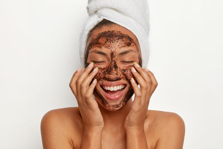 a woman exfoliating her face using coffee face pack