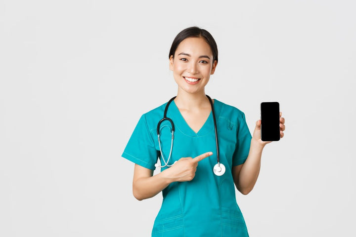 a female doctor pointing towards a phone in her other hand