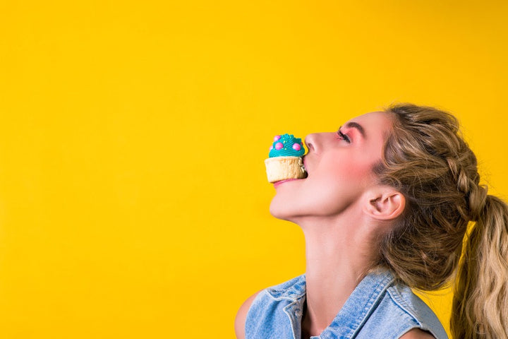 a woman holding a cup cake on her mouth