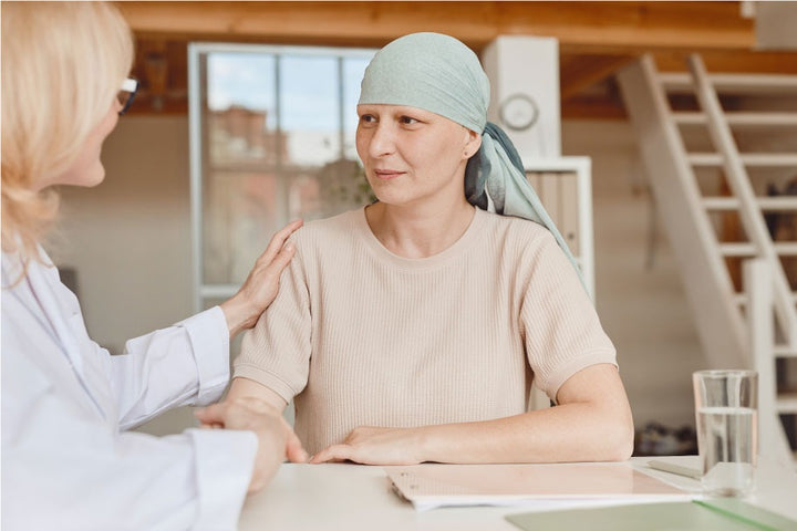 a bald woman undergoing chemotherapy is talking to a doctor